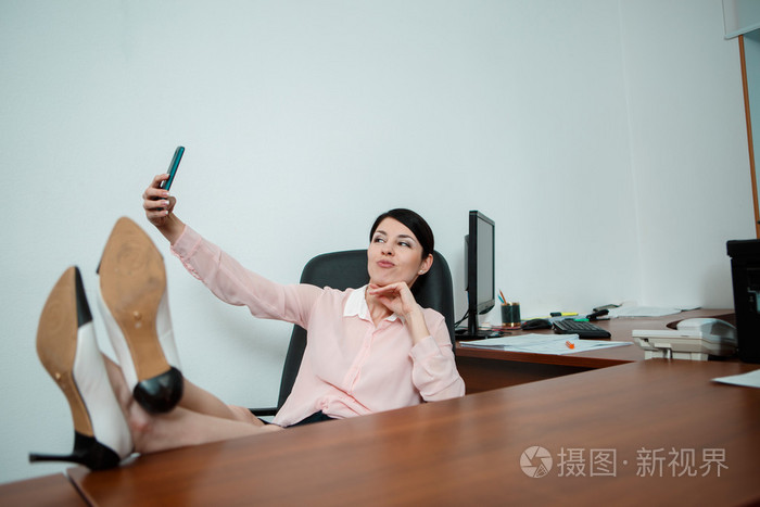 轻松的商务女人坐在椅子上,双腿在桌子上