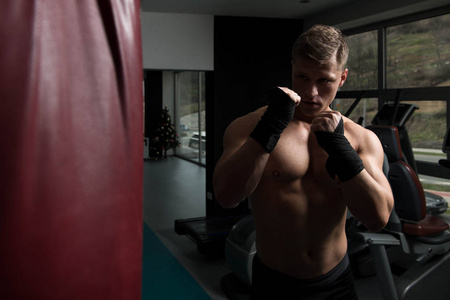 年轻男子拳击袋拳击在健身房健康的生活方式的概念   这个想法关于拳击的电影
