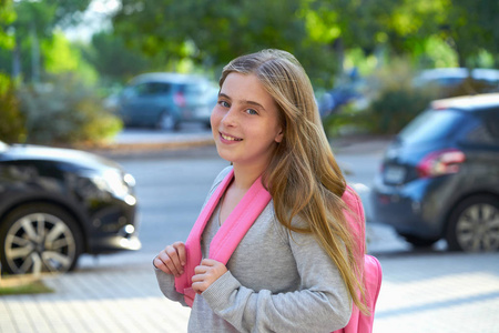 金发女郎的学生女孩背着背包在城市回学校