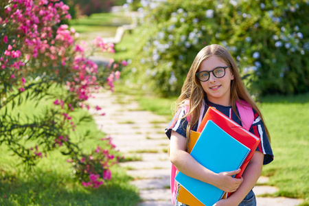金发女郎的学生女孩与眼镜笔记本和背包在公园