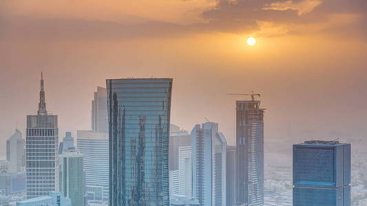在首都卡塔尔多哈商业中心的地平线上, 日落 timelapse 的摩天大楼。在大雾天气的空中俯视图。多云的橙色天空