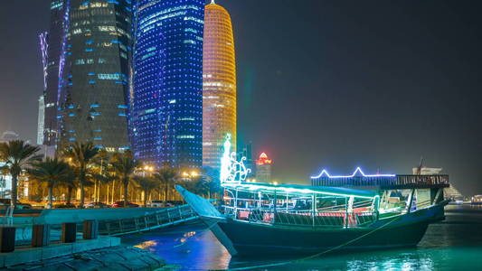 传统的帆船在多哈的夜晚 timelapse, 与现代建筑的背景。从海滨大道上照亮了西海湾的摩天大楼