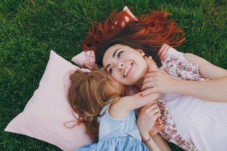 微笑的女人和小可爱的孩子宝贝女孩躺在草地上的枕头上拥抱, 拥抱和休息, 玩得开心。妈妈小女儿母亲节, 爱家庭, 亲子, 童年概念