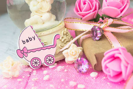 粉红色的木制马车图与包好的礼物。女孩出生概念