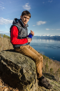 男子坐在一瓶水一湖的自然背景