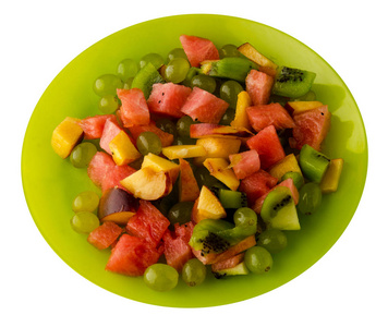水果沙拉. 素食沙拉。西瓜, 猕猴桃, 葡萄, 桃子上的一个盘子上的白色背景. 水果沙拉放在盘子里。健康食品