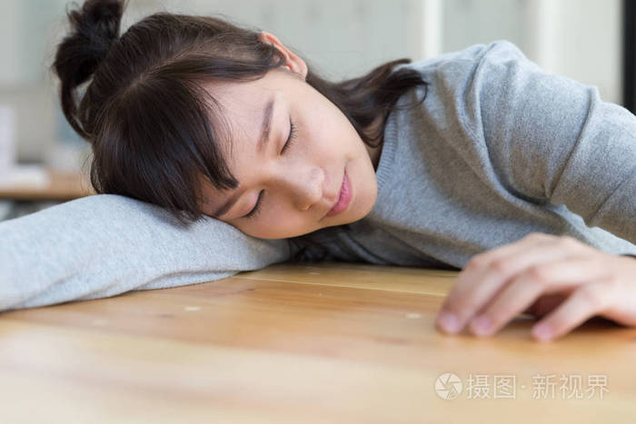 疲倦的学生女孩睡在桌子上.努力学习教育