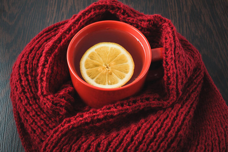 喝杯热茶加柠檬穿着针织温暖冬季围巾 温暖针织毛衫或毯子。静物画的一条围巾和杯加柠檬的茶。冬天的时候。舒适和软冬季背景
