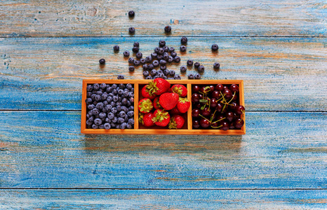 从上面看到的一个蓝色老式木制厨房桌子是一个单独的的形式与不同的糖果和水果主妇在上放置新鲜浆果