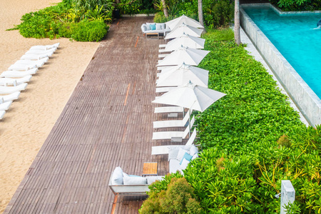 美丽的豪华雨伞和椅子周围的游泳池在酒店和度假村的旅游和度假