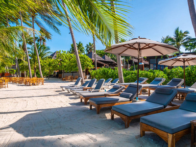 海滩和海洋上的雨伞和椅子, 周围有蓝天, 椰子棕榈树, 用于旅行和度假