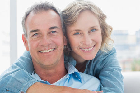 微笑的女人在沙发上从后面拥抱她的丈夫