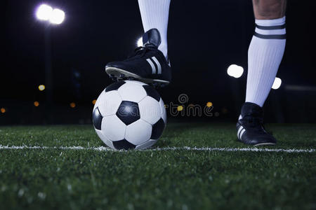 足球线上，晚上在体育场，脚在足球上方的特写镜头