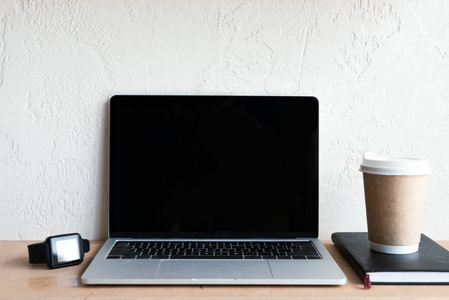 带空白屏幕smartwatch笔记本和咖啡的笔记本电脑去桌上