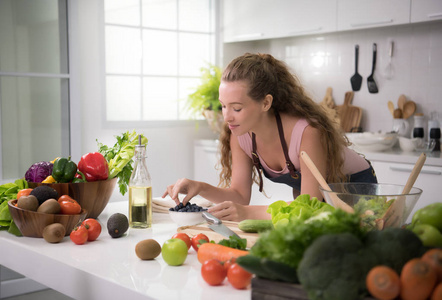 健康的年轻妇女在厨房准备健康的膳食和沙拉蔬菜