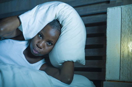 年轻绝望和压力的生活方式的夜肖像躺在床上不安的黑人美国妇女睡在失眠和睡眠障碍问题的头痛和宿醉