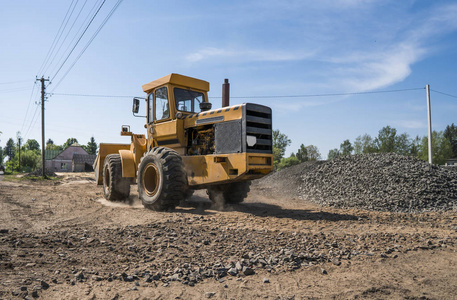 在公路建设工程中, 黄色装载机与碎石一起移动。道路上的石头。卸石