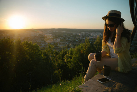 年轻女子坐在一座小山与杯咖啡图片