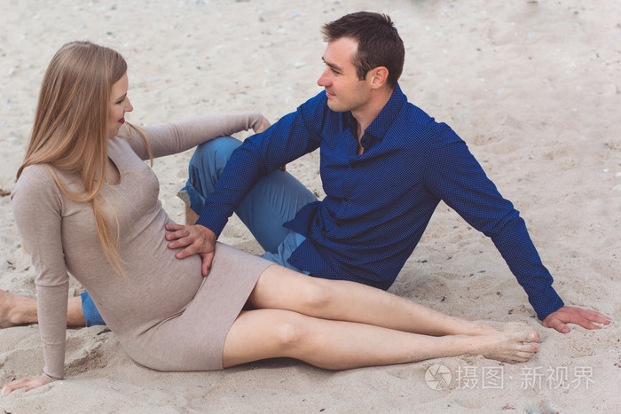 在海滩上休息的男人和怀孕的女人