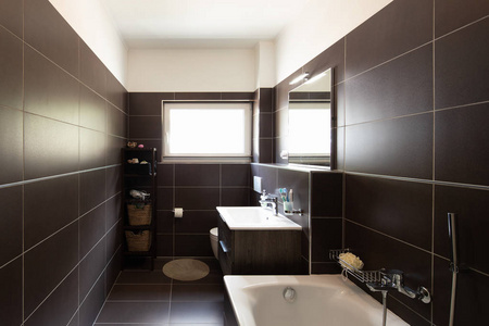 现代浴室与棕色瓷砖和窗口。里面没人
