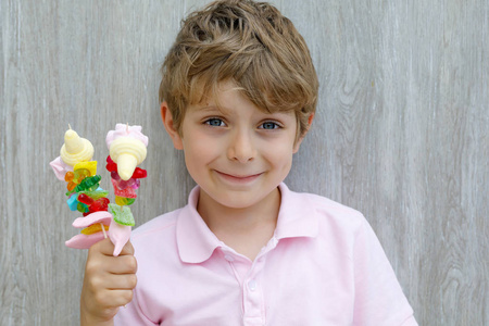 快乐的小小孩男孩手拿棉花糖串。不同的 unhelthy 彩色糖果的孩子