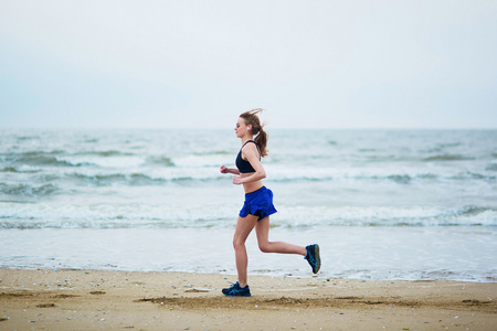 年轻的健身跑在海滩上慢跑的女人
