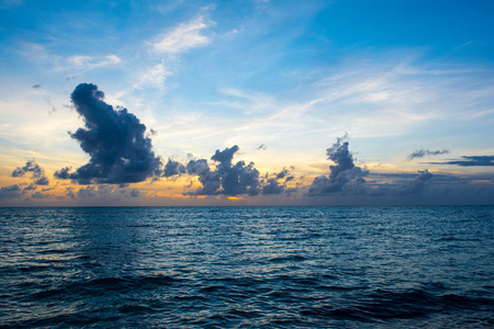 在马尔代夫岛沙质海滩与色彩斑斓的天空和浪的大海上空的云块戏剧性的美丽的日落景观