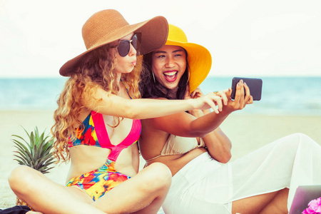 穿着比基尼的快乐女人, 在暑假里把自拍的照片从手机上一起带到热带沙滩上。旅游生活方式