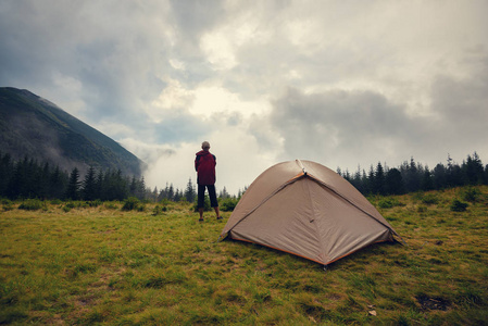 探险家在草地上放松, 在暴风雨后的雾中欣赏山脉。史诗般的旅行在山上。后退视图