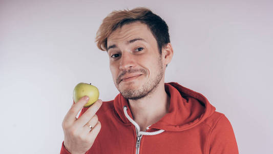 一个性格开朗的人抱着一个绿色的苹果, 在白色的背景上。健康食品的爱情观