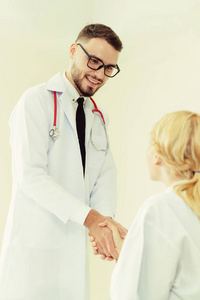 医生在医院向另一位医生握手, 展示了专业医护人员的成功和团队精神。