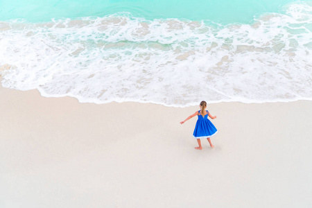 可爱的小女孩，在白色的热带海滩上跳舞。查看从上面的一个空旷的海滩与绿松石水