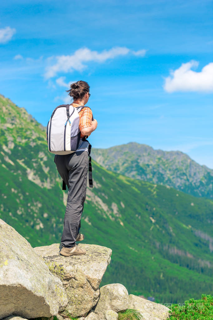 从一个游客的背部与一个背包在山上的悬崖上观看