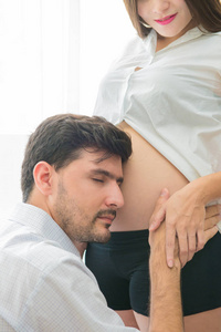 孕妇和她英俊的丈夫听婴儿在