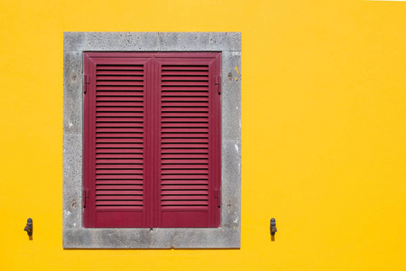 黄色外墙与一个带有红色快门的窗口