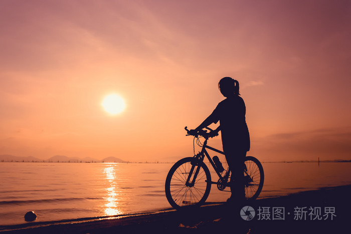 健康的骑自行车的人女孩享受着在海边景色的轮廓