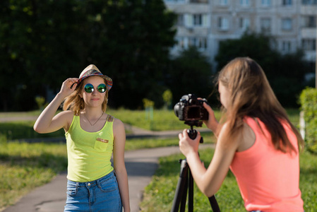 夏天的两个女学生在公园里记录录像。她穿着鲜艳的衣服, 戴着帽子和太阳镜。年轻博客的概念