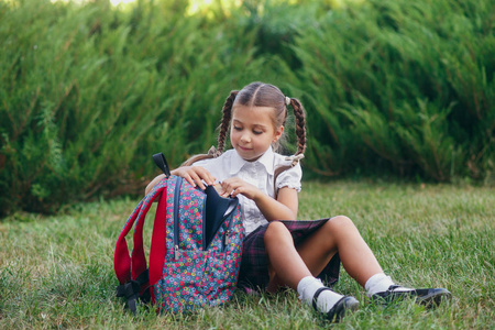 小女孩坐在草地上看书。小学生小学