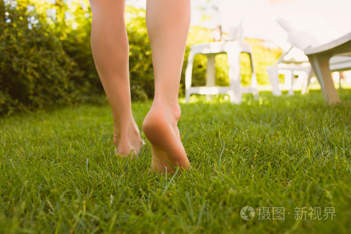 关闭在草地上行走的女性双腿