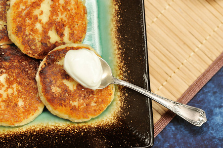健康早餐新鲜烘烤的小屋乳酪煎饼与酸奶油在板材特写