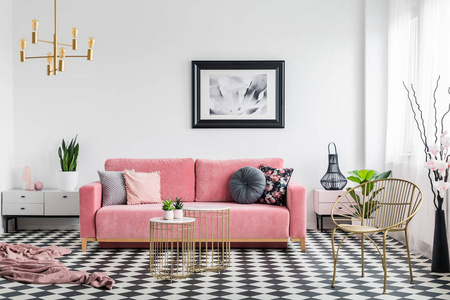 真实照片的魅力客厅内部与粉粉红色的沙发, 格子地板, 海报和金属咖啡桌