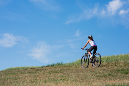 运动自行车女子在草地上与一个美丽的风景