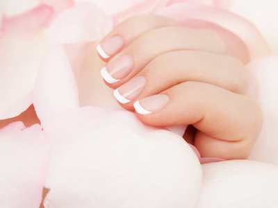 修指甲, 手水疗美丽的女人手, 柔软的皮肤, 美丽的指甲与粉红色的玫瑰花花瓣。健康的女人手。美容院。美容治疗。女性指甲, 漂亮的