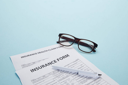 保险形式保险健康索赔表眼镜和钢笔的特写查看蓝色