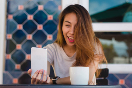 迷人的美丽的年轻的亚洲妇女自拍使用智能手机在咖啡馆。年轻的亚洲女孩在餐馆采取自画像