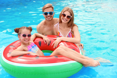 快乐的家庭在游泳池在晴朗的天