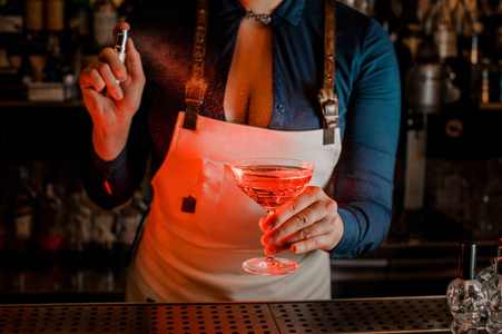 热女酒保与深领口喷涂苦涩的优雅鸡尾酒玻璃充满美味和甜美的粉红色夏日饮料