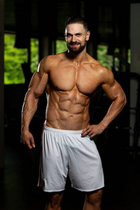 英俊的年轻男子站在健身房和肌肉伸缩强运动后的肌肉运动健美健身模特