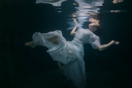 穿着白色连衣裙的漂亮女人在水下
