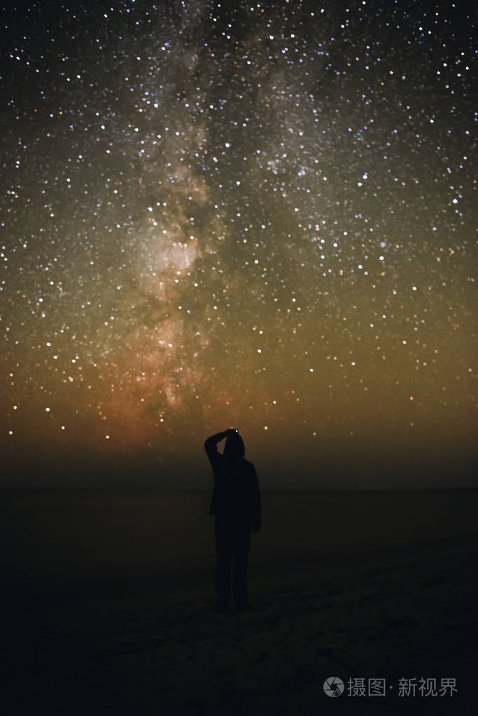 一个孤独的男人的剪影站在海边 看着星空与银河